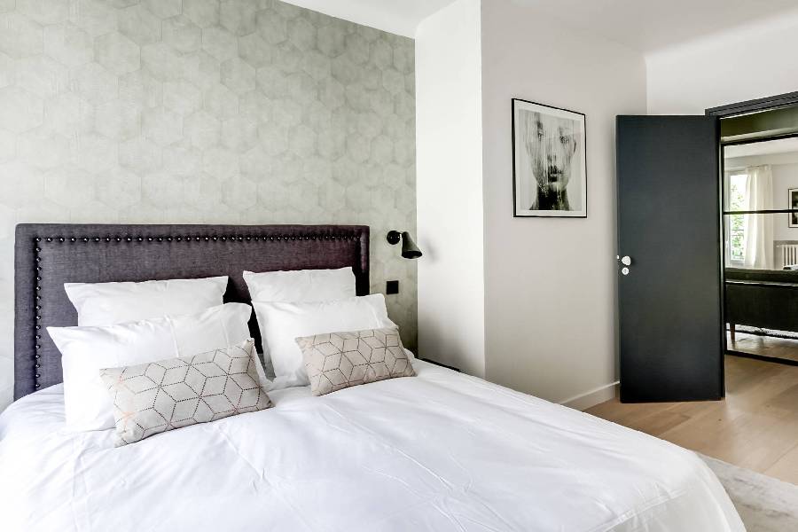 HDB BTO bedroom with hexagon-pattern wallpaper feature wall and dark tufted headboard