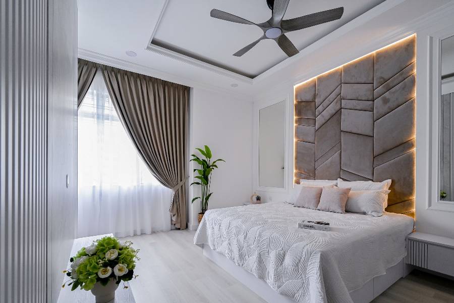 Bright bedroom with tufted grey channel headboard feature wall and ceiling fan