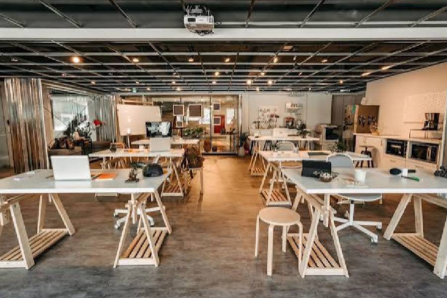 Collaborative office workspace with trestle desks and breakout area